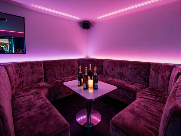 Upscale Miami nightclub VIP booth with neon lighting and champagne for cougar dating nights
